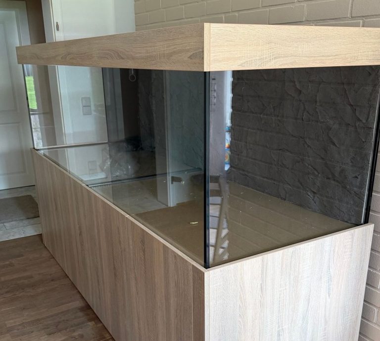 Aquarium im Wohnzimmer mit bunten Fischen und Steinen als Dekoration