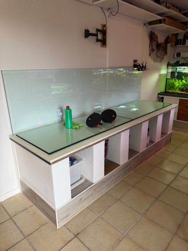Ein großes, leeres Aquarium auf einem weißen Unterschrank steht in einem Raum.
