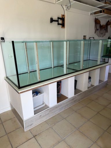 Ein großes, leeres Aquarium auf einem weißen Unterschrank steht in einem Raum.