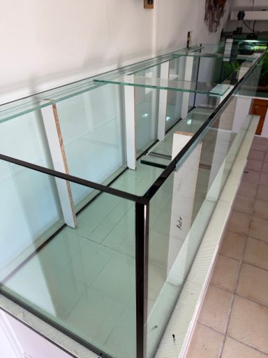 Ein großes, leeres Aquarium auf einem weißen Unterschrank steht in einem Raum.