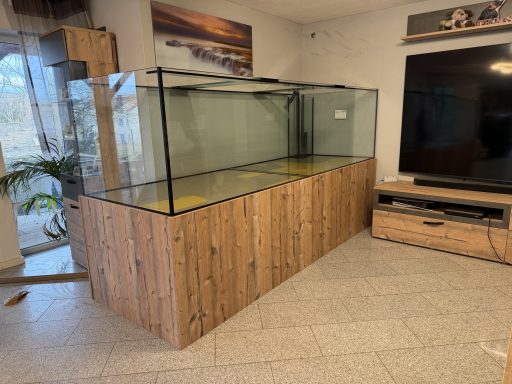 Großes Aquarienbecken mit Holzverkleidung in einem modernen Wohnraum.
